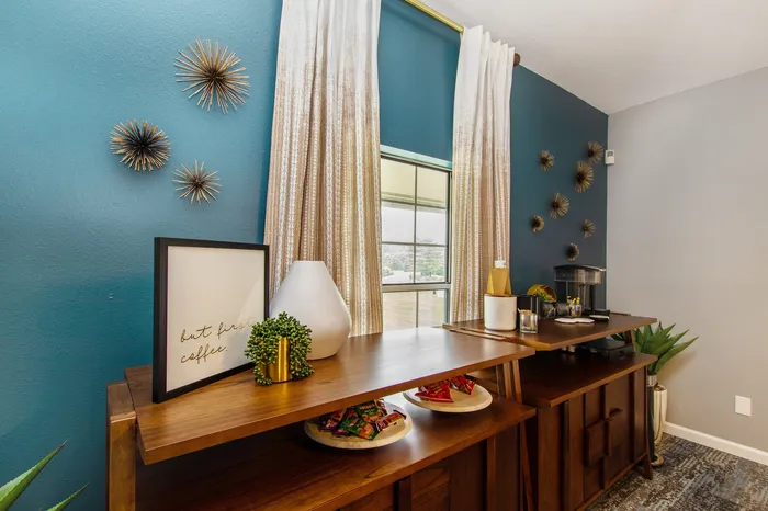 Chic apartment coffee station with modern decor, featuring a wooden counter, artistic wall accents, and large windows allowing natural light.