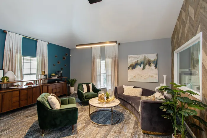 Elegant living room with modern furnishings including plush sofas, a stylish coffee table, vibrant wall art, and greenery, creating a cozy and inviting atmosphere.