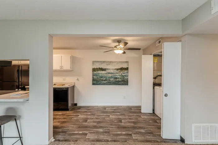Charming open-concept kitchen and dining area with modern ceiling fan, stylish laminate flooring, and elegant wall art.