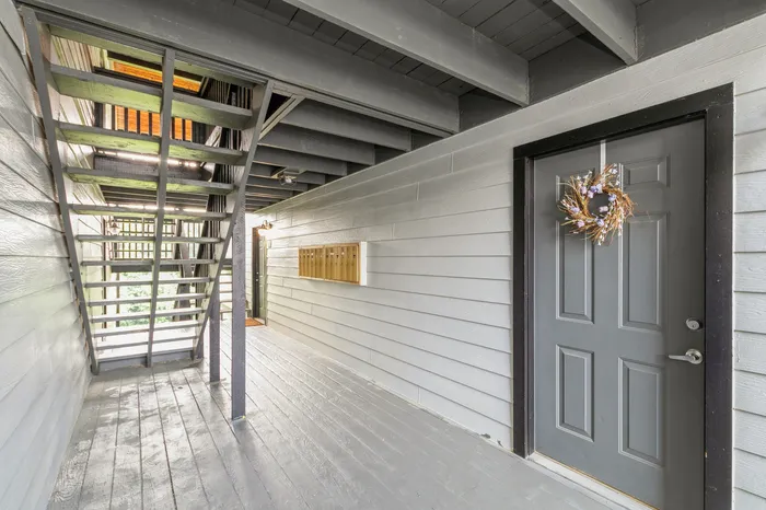 Inviting apartment entrance with charming wreath and modern gray door, complemented by sleek architecture.