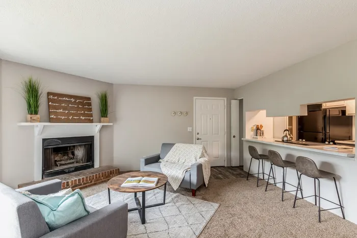 Inviting living space featuring a cozy fireplace, modern seating area, and open kitchen bar with stylish stools, ideal for relaxation and entertaining.