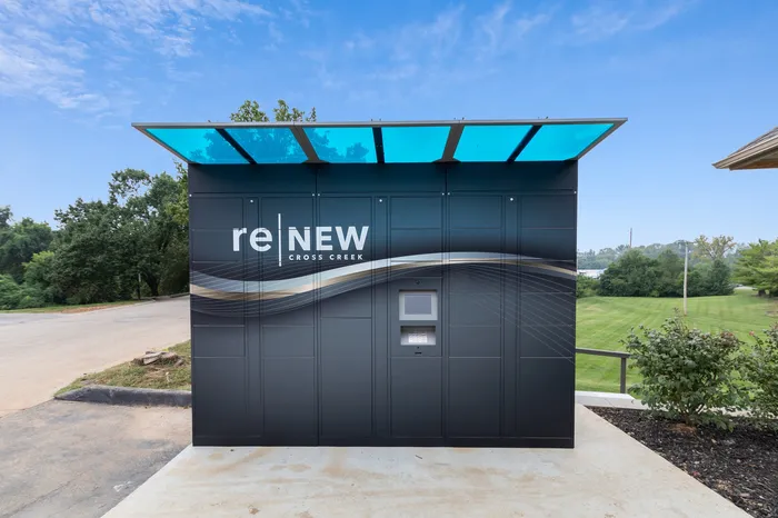 Sleek modern parcel locker at reNEW Cross Creek set against a lush green landscape under a clear blue sky.