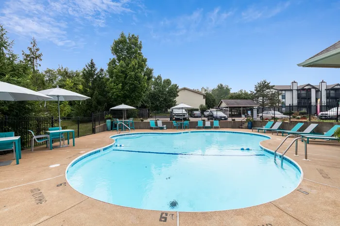 Inviting outdoor swimming pool with elegant lounge chairs and umbrellas, surrounded by lush greenery and modern architecture.