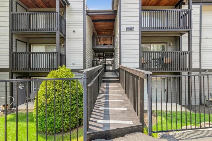 Modern apartment exterior with inviting walkway, spacious balconies, and lush greenery for a welcoming atmosphere.