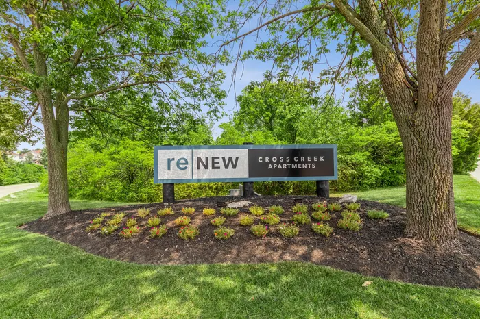 Inviting entrance sign for Cross Creek Apartments, surrounded by lush greenery and vibrant landscaping.