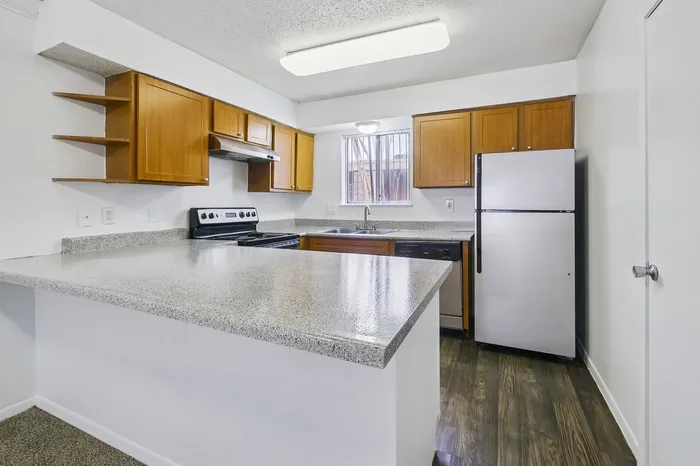 Modern kitchen with sleek granite countertops, wooden cabinetry, stainless steel appliances, and bright lighting offers a welcoming culinary space.