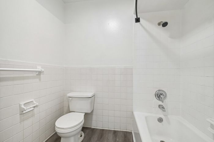 Bright and clean bathroom with modern tiling, featuring a relaxing bathtub and sleek toilet, perfect for comfort and style.