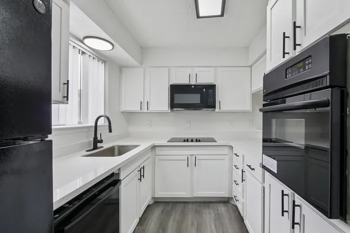 Modern kitchen with sleek black appliances, pristine white cabinetry, and elegant fixtures, showcasing a sophisticated and functional design.