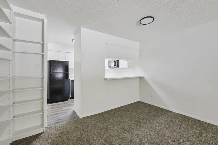 Chic and cozy apartment interior with contemporary kitchen, sleek black appliances, and inviting carpeted living space.