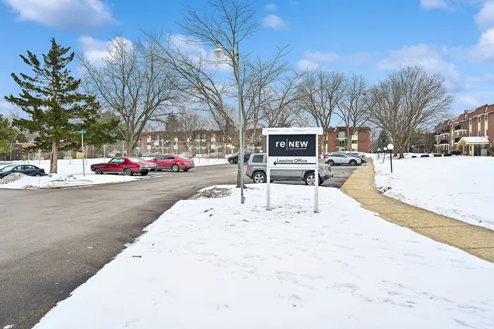 Charming apartment leasing office surrounded by snowy serenity, inviting pathways, and modern residential buildings.