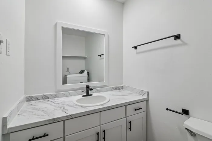 Elegant bathroom featuring a sleek marble countertop, modern fixtures, and a stylish vanity mirror.