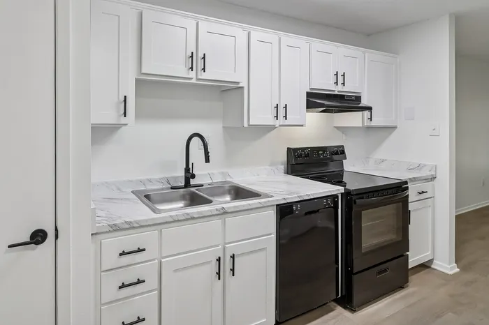 Modern kitchen with sleek black appliances, white cabinetry, and elegant marble countertops.