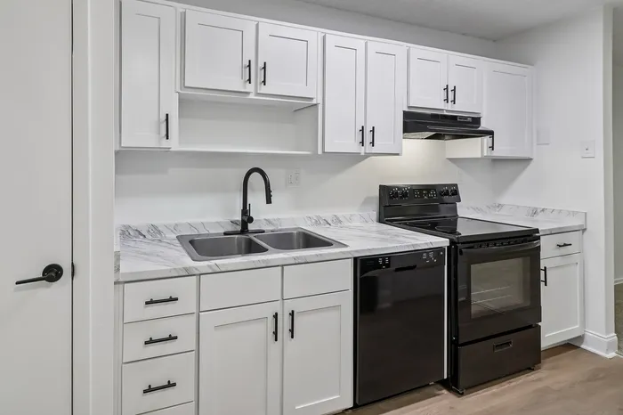 Contemporary kitchen with sleek white cabinets, elegant marble countertops, and modern black appliances.