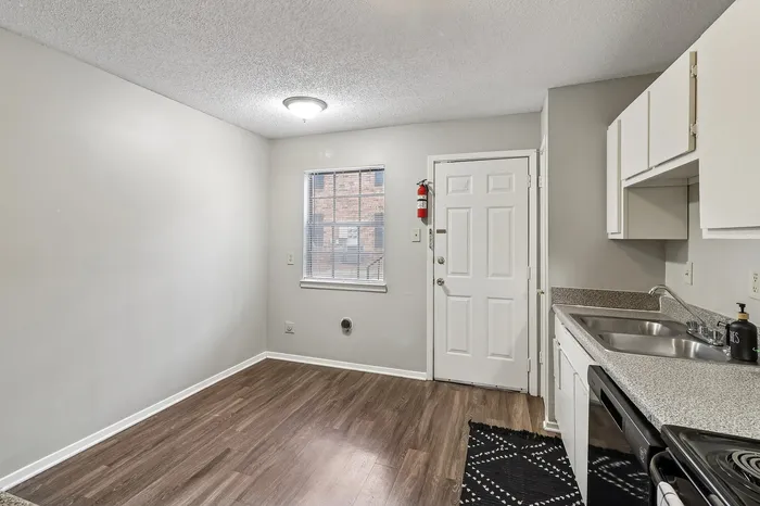 Inviting kitchen area with sleek countertops and modern appliances, complemented by warm wood flooring and natural light from a charming window.