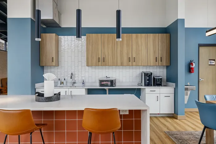 Modern kitchen with sleek cabinets, stylish pendant lighting, and an inviting breakfast bar with orange-accented design.