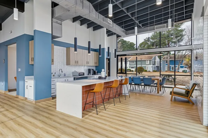 Modern, bright, open-concept kitchen and dining area with chic pendant lighting, sleek cabinetry, and large windows revealing scenic outdoor views.