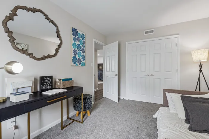 Chic apartment interior showcasing a stylish office nook with modern decor, elegant lighting, and a plush carpeted floor.
