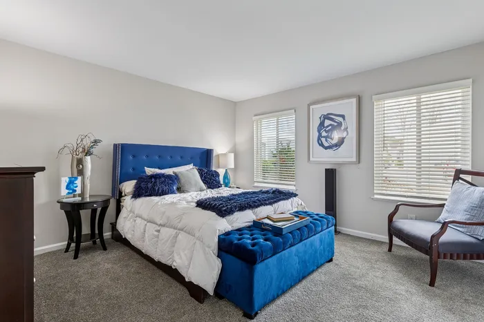 Elegant bedroom with a plush blue headboard, luxurious linens, and stylish decor, offering comfort and tranquility.