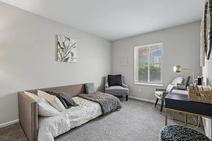 Cozy and elegant room with a stylish sofa, plush chairs, and large window letting in natural light, perfect for relaxation or study.