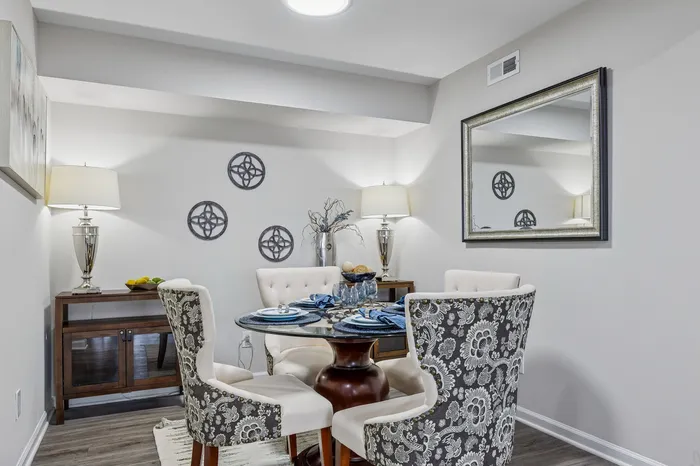 Inviting dining area with elegant upholstered chairs and a glass-top table, featuring tasteful wall decor and ambient lighting.