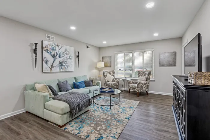 Inviting living room with stylish decor, featuring a plush sectional sofa, patterned armchairs, and a large window letting in natural light.