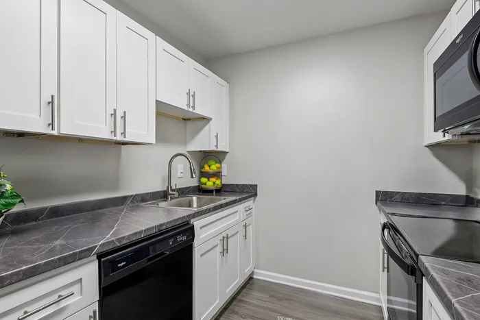 Contemporary kitchen with sleek white cabinets and luxurious marble countertops, featuring modern appliances for an elegant cooking experience.