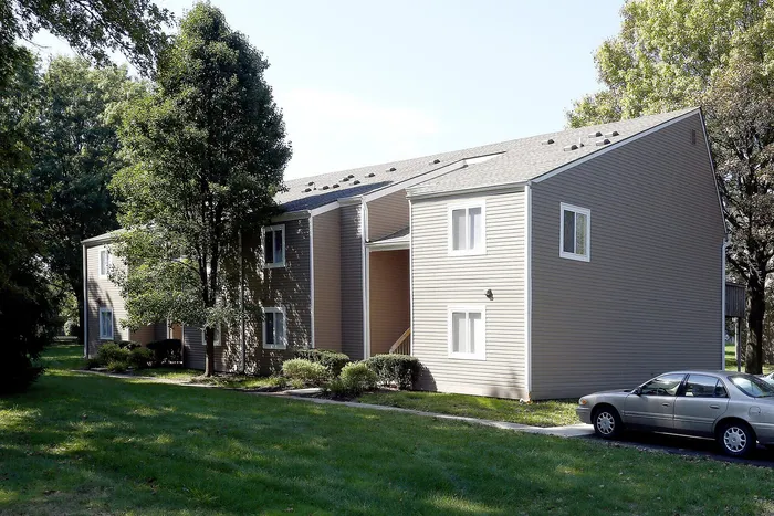 Charming two-story apartment building surrounded by lush greenery, perfect for serene living.