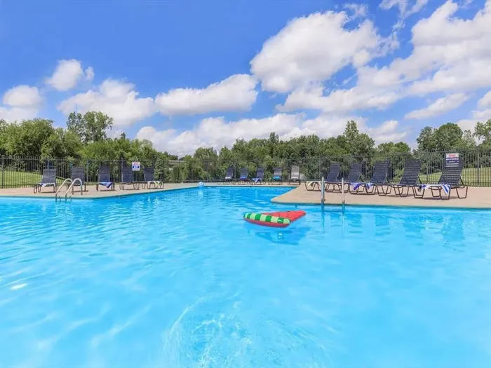 Inviting outdoor pool area with crystal-clear water, surrounded by comfortable lounge chairs under a bright blue sky.