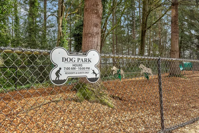 Inviting dog park surrounded by lush trees, featuring a playful space for residents' pets to enjoy, open daily from 7 AM to 10 PM.
