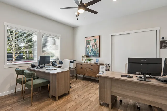 Modern office space with stylish wooden desks, sophisticated decor, large windows, and plentiful natural light.