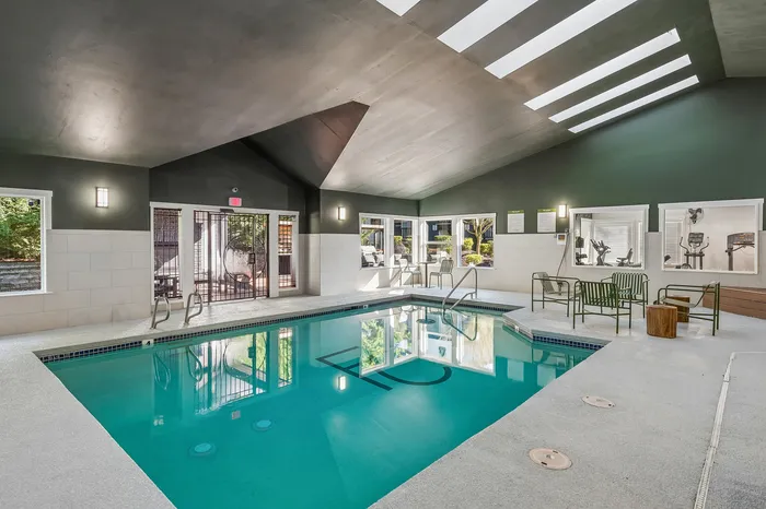 Luxurious indoor pool area with modern seating and skylights, offering a relaxing retreat in a stylish setting.