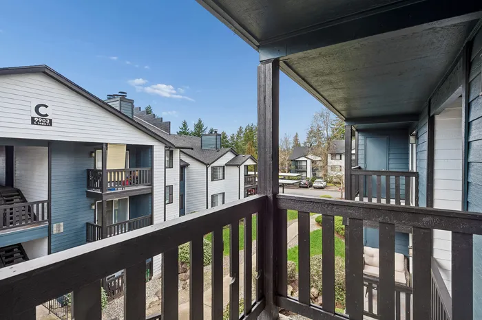 Charming balcony view overlooking modern apartments with lush green surroundings and clear blue sky, perfect for serene living.