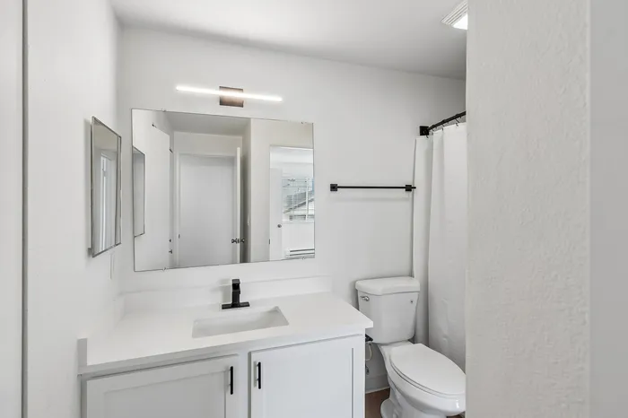 Sleek, modern bathroom with a polished vanity, large mirror, and elegant lighting, creating a bright and inviting space.