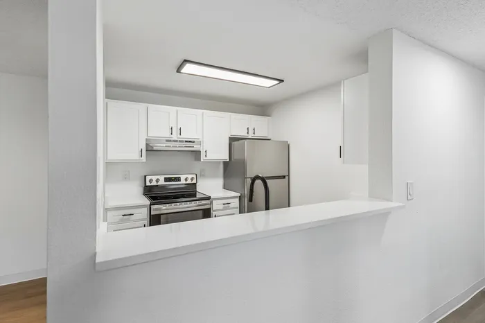 Modern kitchen with sleek white cabinets, stainless steel appliances, and a stylish breakfast bar, perfect for contemporary living.