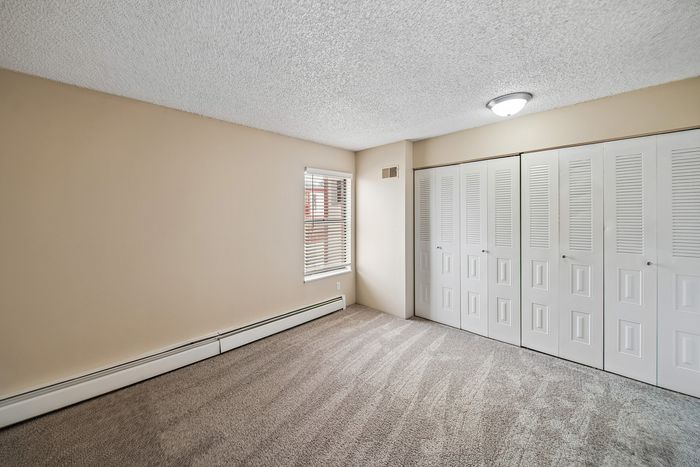 Spacious and bright room with plush carpet, ample closet space, and natural light from a well-positioned window.