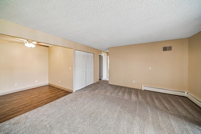 Bright and inviting living area with plush carpeting and elegant ceiling fan, ideal for comfortable living.