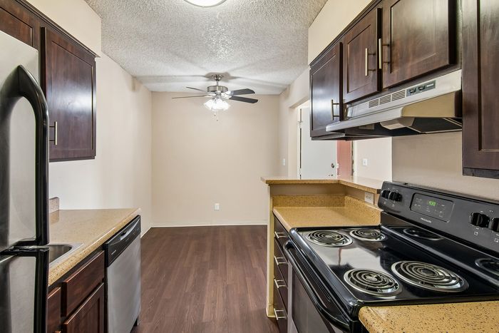 Modern kitchen with sleek dark wood cabinetry, granite countertops, and stainless steel appliances adjacent to a cozy dining area with elegant lighting.