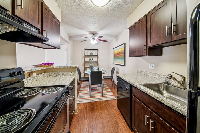 Modern kitchen with sleek dark wood cabinetry, granite countertops, and elegant dining area, offering a stylish and functional space for culinary creativity.