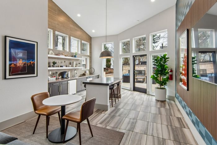 Stunning modern kitchen with large windows, sleek countertops, stylish pendant light, and an inviting dining area with contemporary chairs.