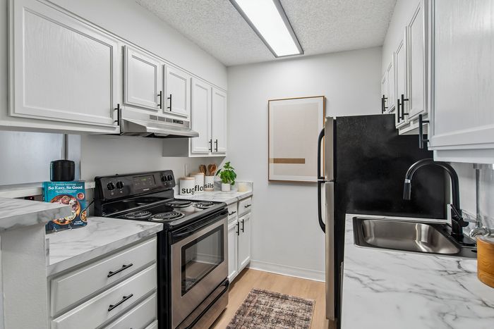 Modern kitchen with sleek white cabinetry, stylish marble countertops, stainless steel appliances, and chic decor.