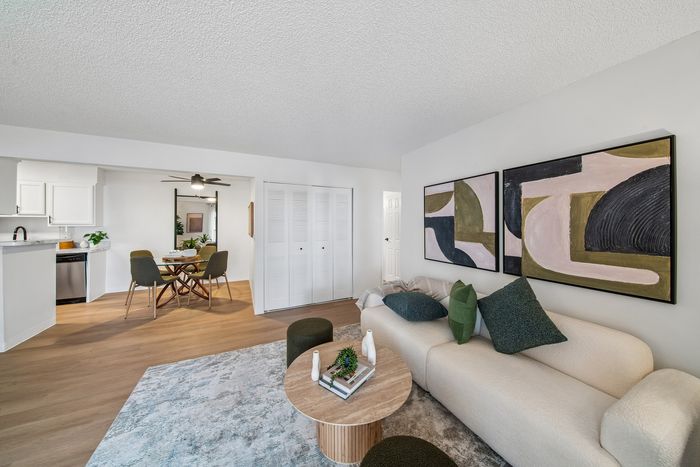 Stylish living room with modern art, cozy seating, open layout leading to a chic dining area next to a contemporary kitchen.