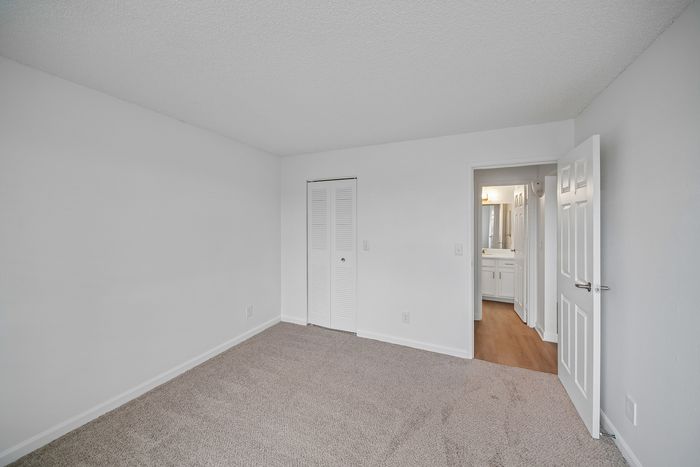 Bright, freshly painted bedroom with soft carpeting and a view into a modern bathroom.
