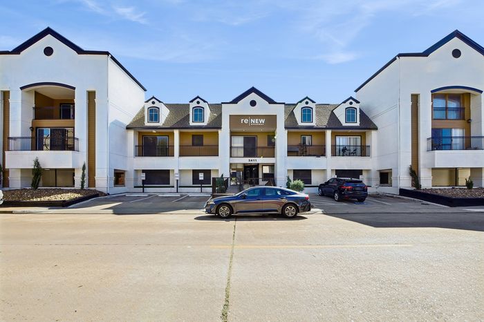Modern apartment complex with a charming exterior and ample parking, showcasing a blend of contemporary architecture and welcoming design.
