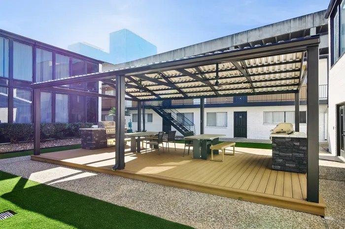 Inviting outdoor covered patio with modern seating and built-in barbecue in a contemporary apartment complex.