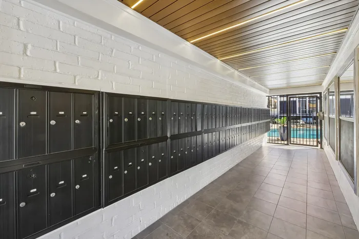 Modern apartment mailroom with sleek metal mailboxes and bright lighting, offering a secure and stylish entryway.