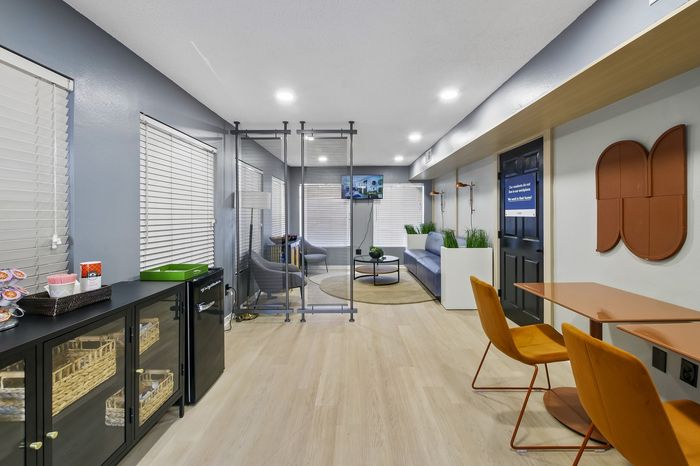 Modern multi-purpose room with sleek furnishings, vibrant orange chairs, and stylish decor, perfect for relaxation and meetings.
