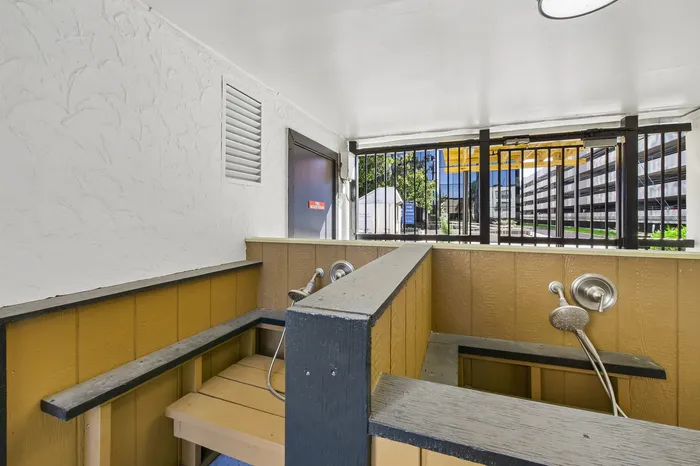 Bright and functional outdoor pet washing station with modern fixtures, featuring secure railing and natural light.