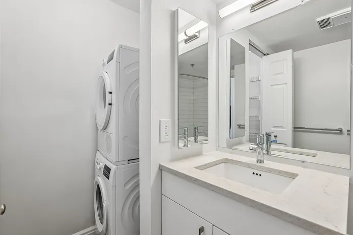 Chic bathroom with modern fixtures and integrated laundry facilities, showcasing efficient use of space.