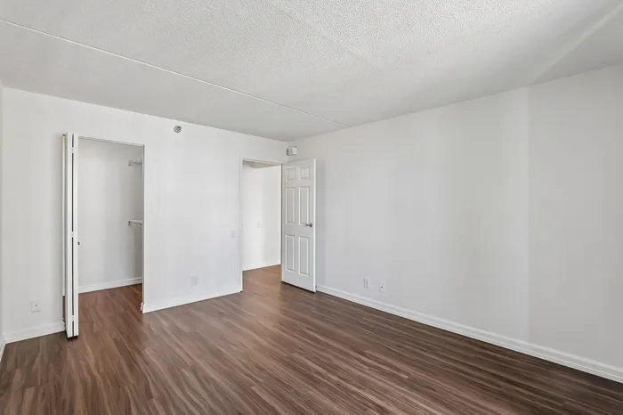 Bright and spacious room with elegant wood flooring and fresh white walls, perfect for a modern apartment setting.
