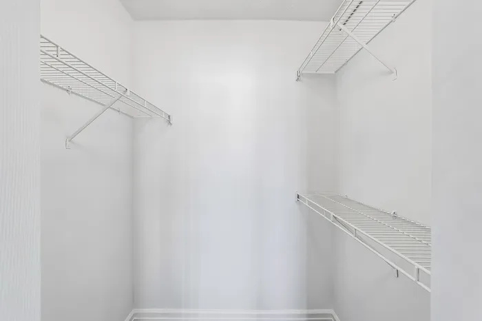 Spacious walk-in closet with sleek white shelving, offering ample storage and a modern touch.